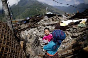 epaselect epa04729942 A picture made available 02 May shows a woman carrying her baby through what is left of Barpak village, epicenter of the devastating earthquake that hit the country on 25 April 2015, Nepal, 01 May 2015. The confirmed official death toll increased to 6,621, with more than 14,000 injured, an Interior Ministry spokesman said. The 7.8-magnitude earthquake was the deadliest in the country for more than 80 years, destroying an estimated 300,000 houses across northern Nepal.  EPA/DIEGO AZUBEL